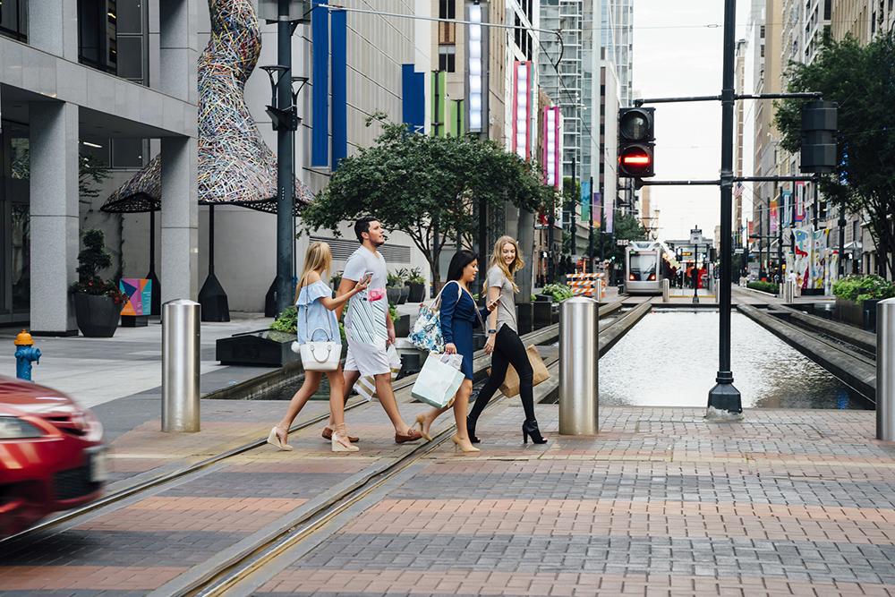 Friends crossing street in city carrying shopping bags